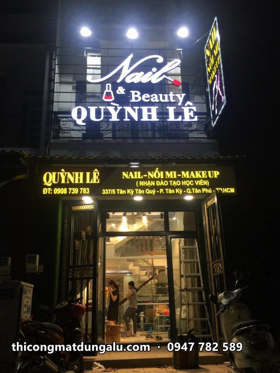 Mặt tiền Nail and Beauty Quỳnh Lê ban đêm với logo sáng và biển chữ vàng