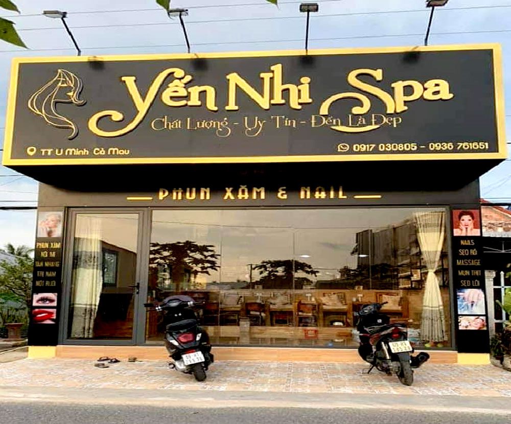 Mặt tiền spa nền đen chữ inox vàng viết tay chạy ngang