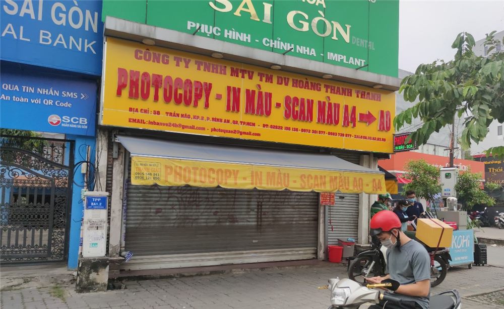 Bảng hiệu photocopy in màu nền vàng chữ đỏ trên mái hiên