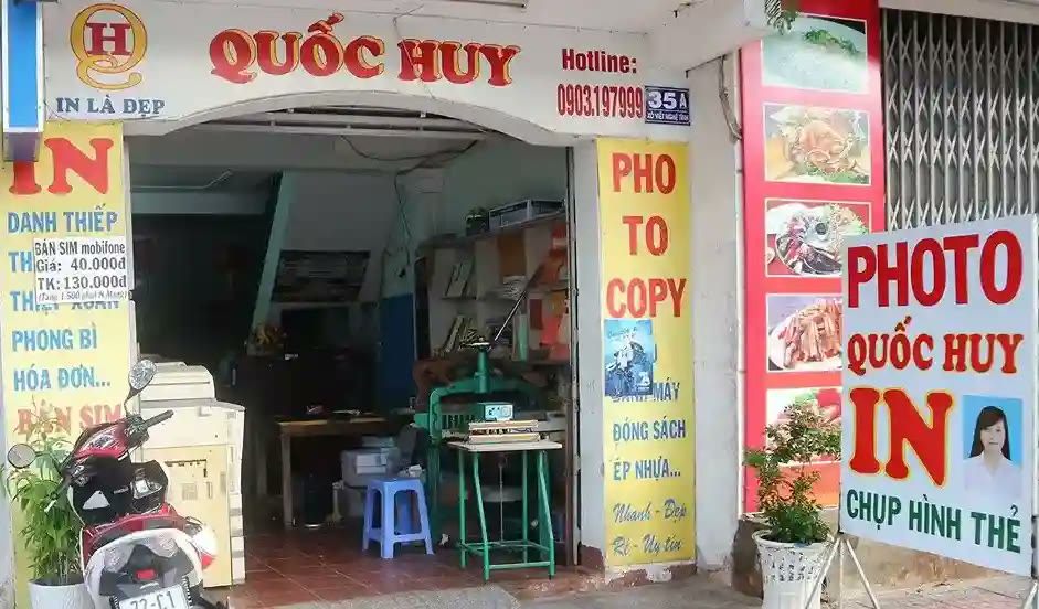 Tiệm in ấn nhỏ với biển dọc nhiều màu ghi in, photocopy, chụp hình thẻ