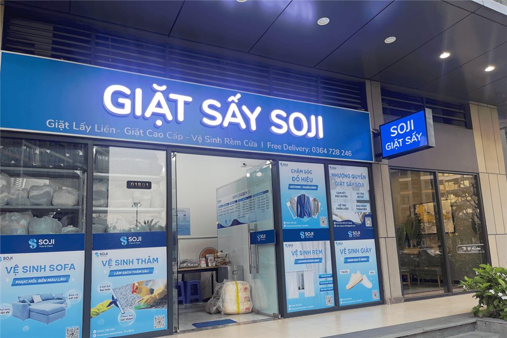 Tiệm giặt sấy ở tầng trệt chung cư với bảng xanh dương chữ trắng và cửa kính dán decal
