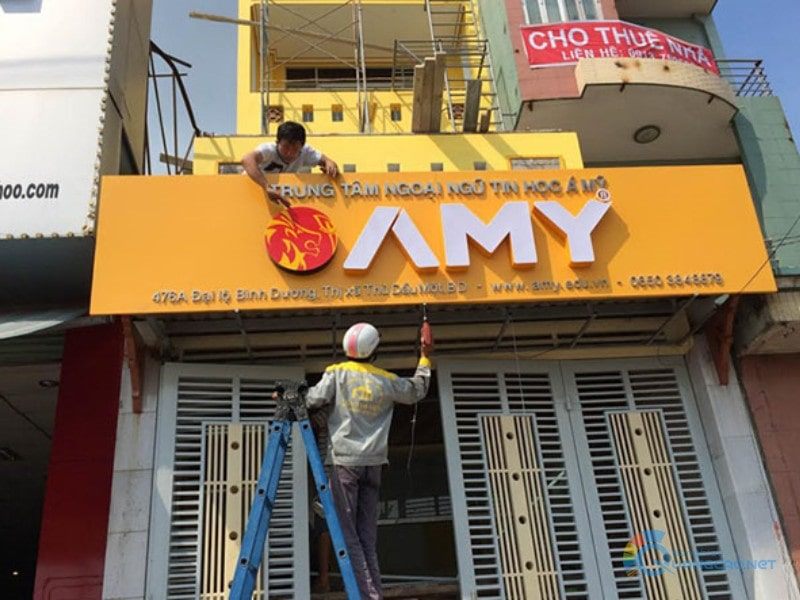 Thợ đang lắp chữ nổi lên bảng hiệu trung tâm ngoại ngữ nền vàng