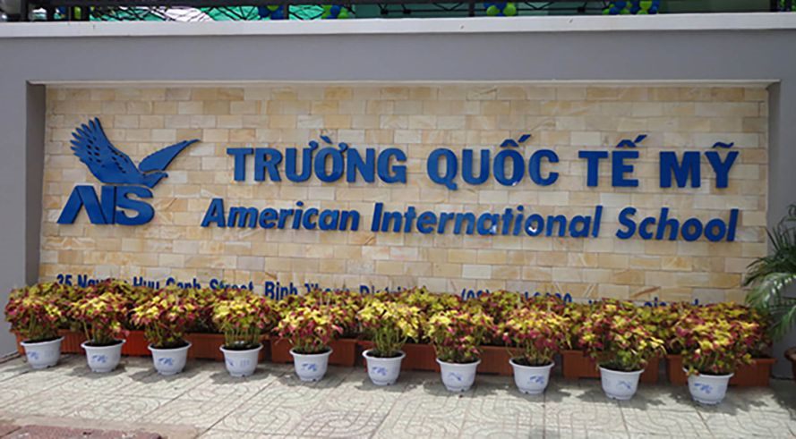 Bảng tên trường quốc tế chữ nổi xanh và logo trên tường ốp gạch