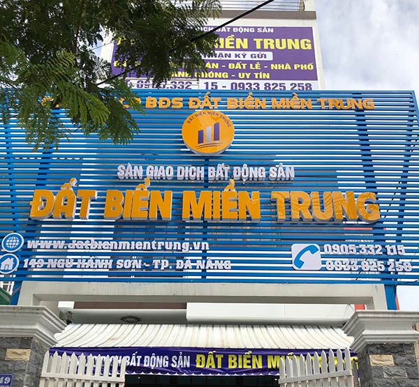 Mặt tiền sàn giao dịch bất động sản nền xanh, chữ vàng, logo tròn và website