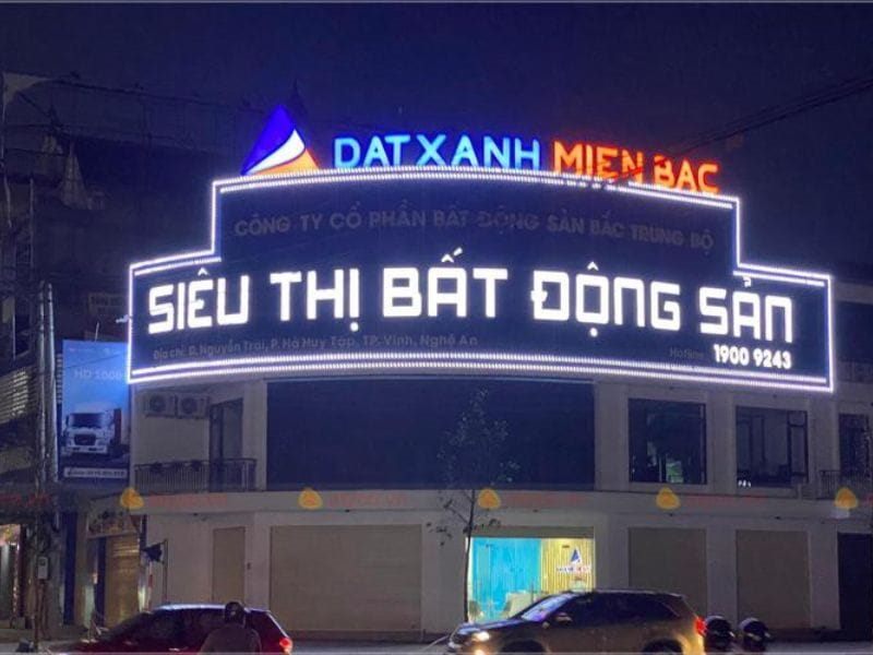 Sàn giao dịch bất động sản ban đêm với chữ LED trắng viền khung cong trên tầng