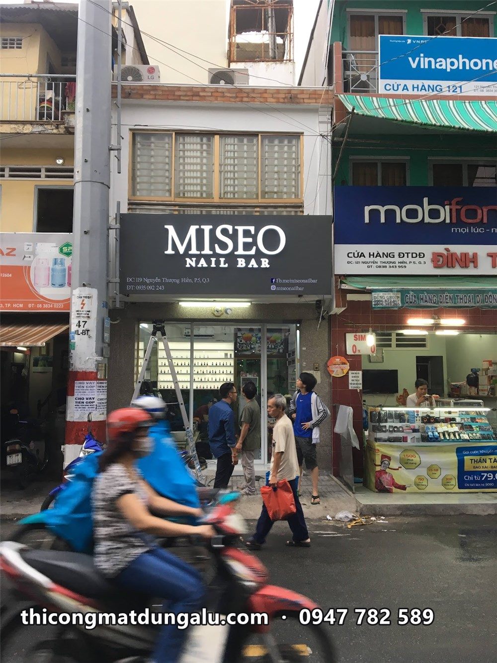 Miseo Nail Bar trên phố đông, bảng hiệu đen giữa các cửa hàng