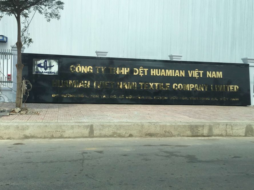 Bức tường bảng tên công ty dệt dài dọc mặt đường
