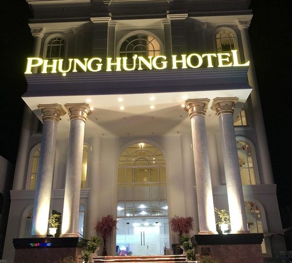 Khách sạn về đêm với chữ nổi vàng sáng trên mái sảnh cột tròn