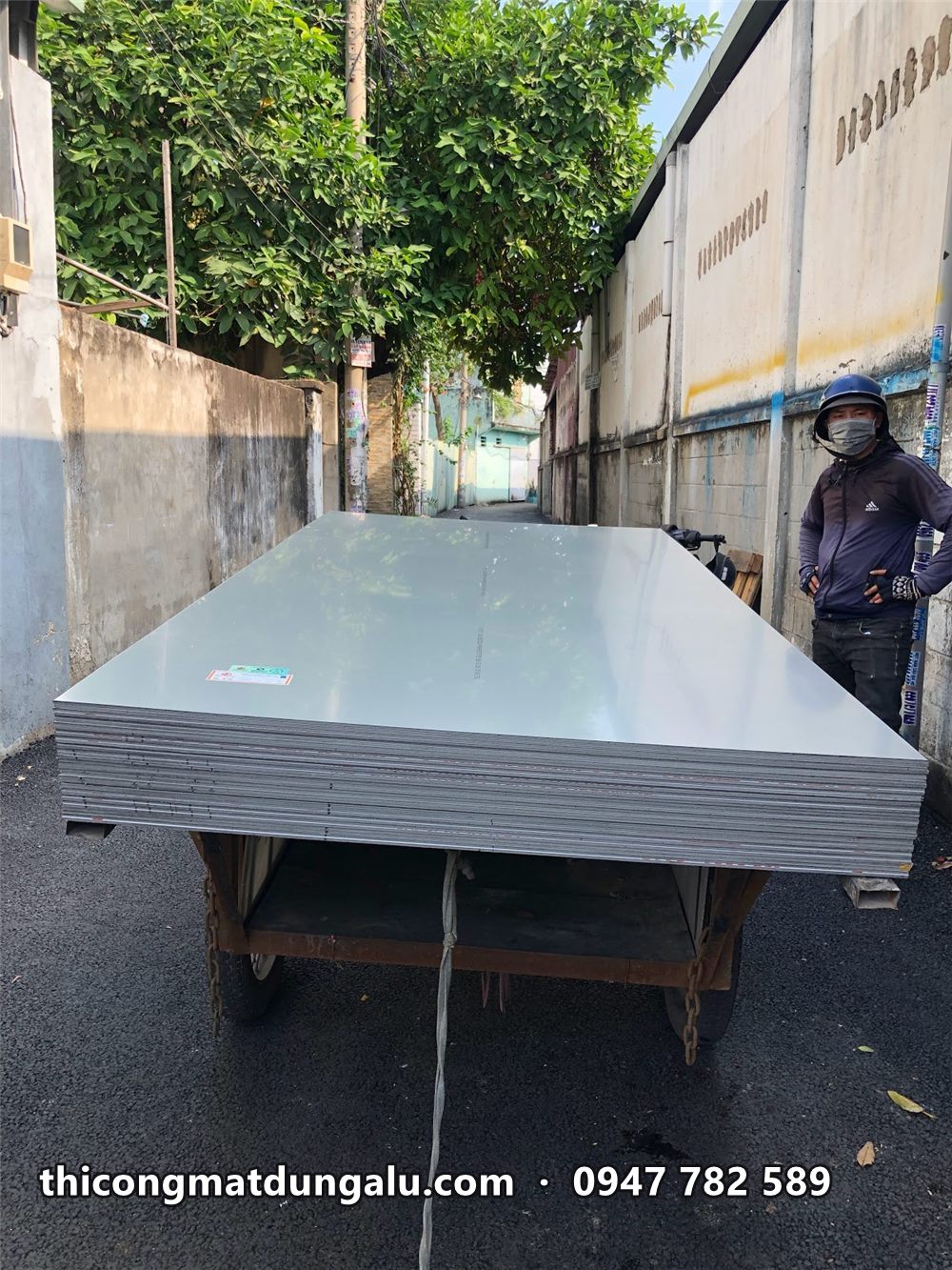 Xe đẩy chở chồng tấm alu khổ lớn trong hẻm trước xưởng