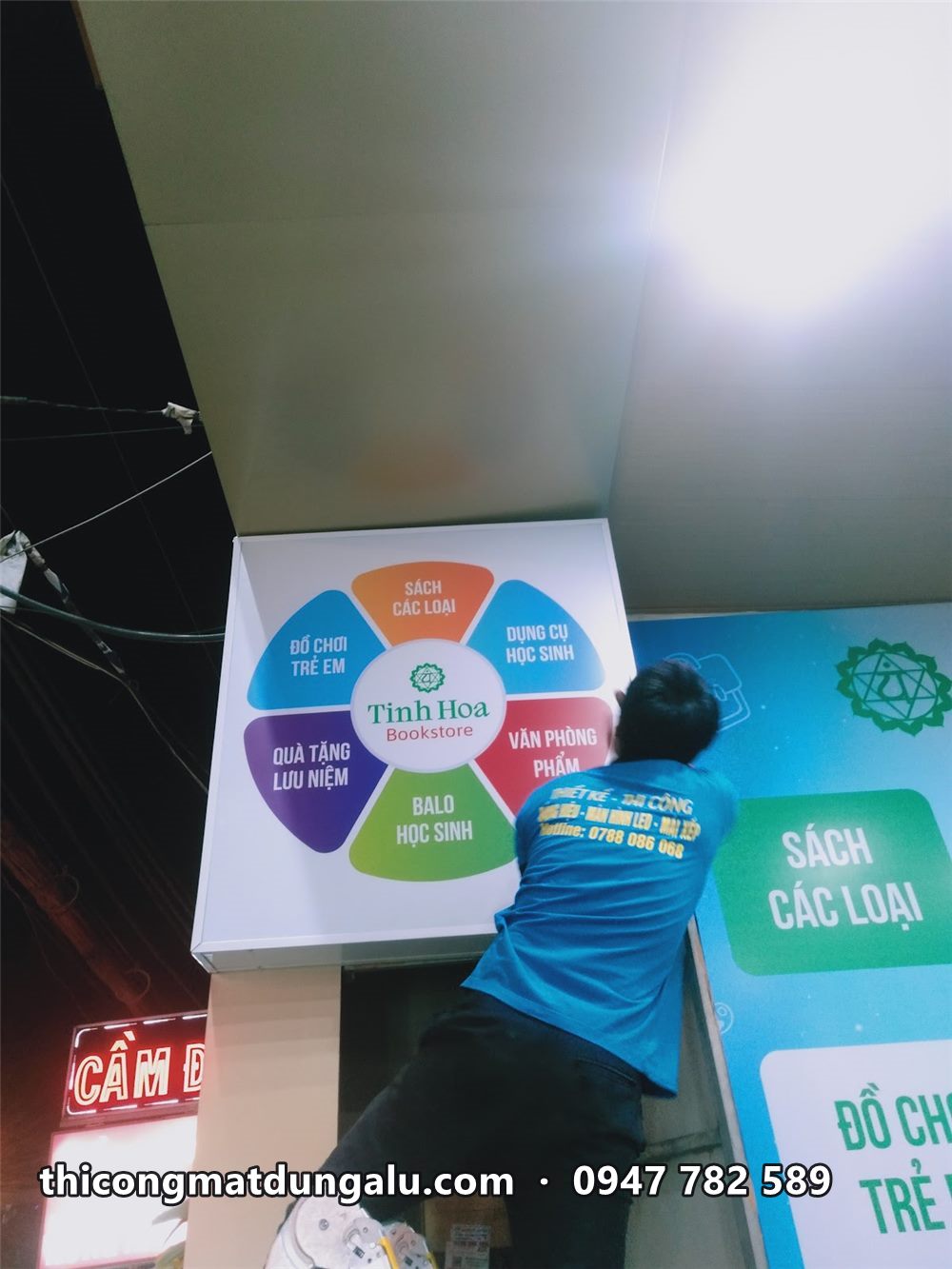 Thợ lắp hộp đèn tròn sáu màu lên đầu cột lúc tối
