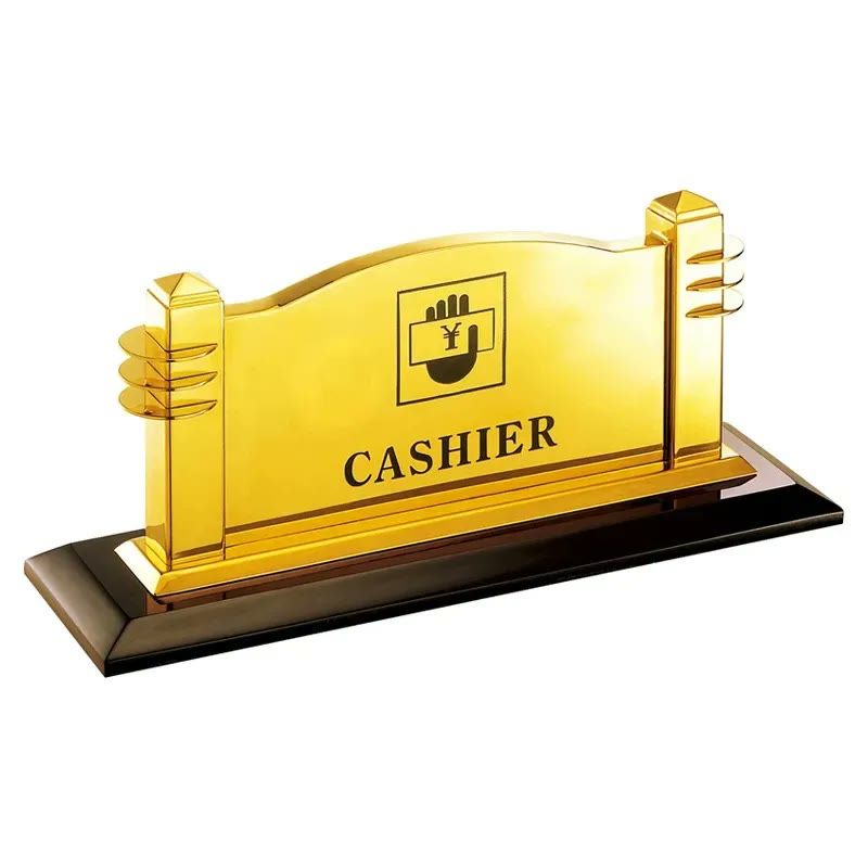 Biển chức danh kim loại mạ vàng có đế đen, khắc chữ Cashier và biểu tượng