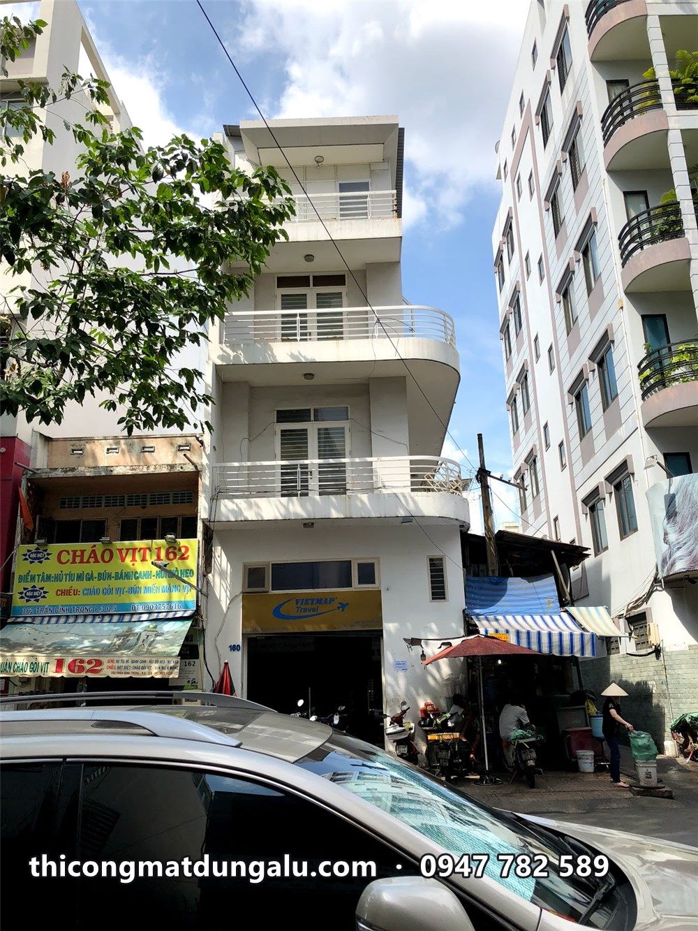Nhà phố góc đường nhiều tầng với ban công cong và lan can trắng kiểu cũ