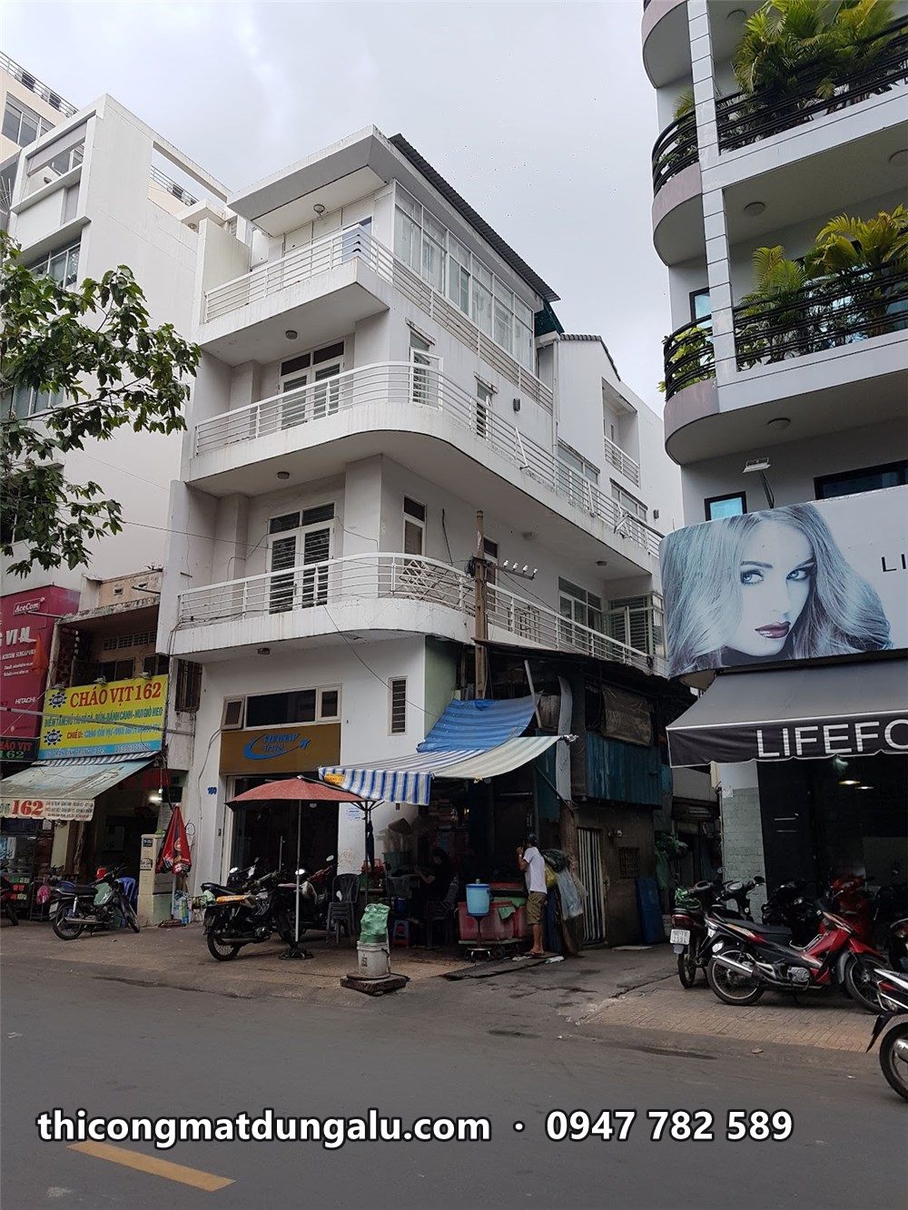 Góc nhà phố nhìn từ ngã tư, ban công cong ở các tầng, cửa hàng tầng trệt