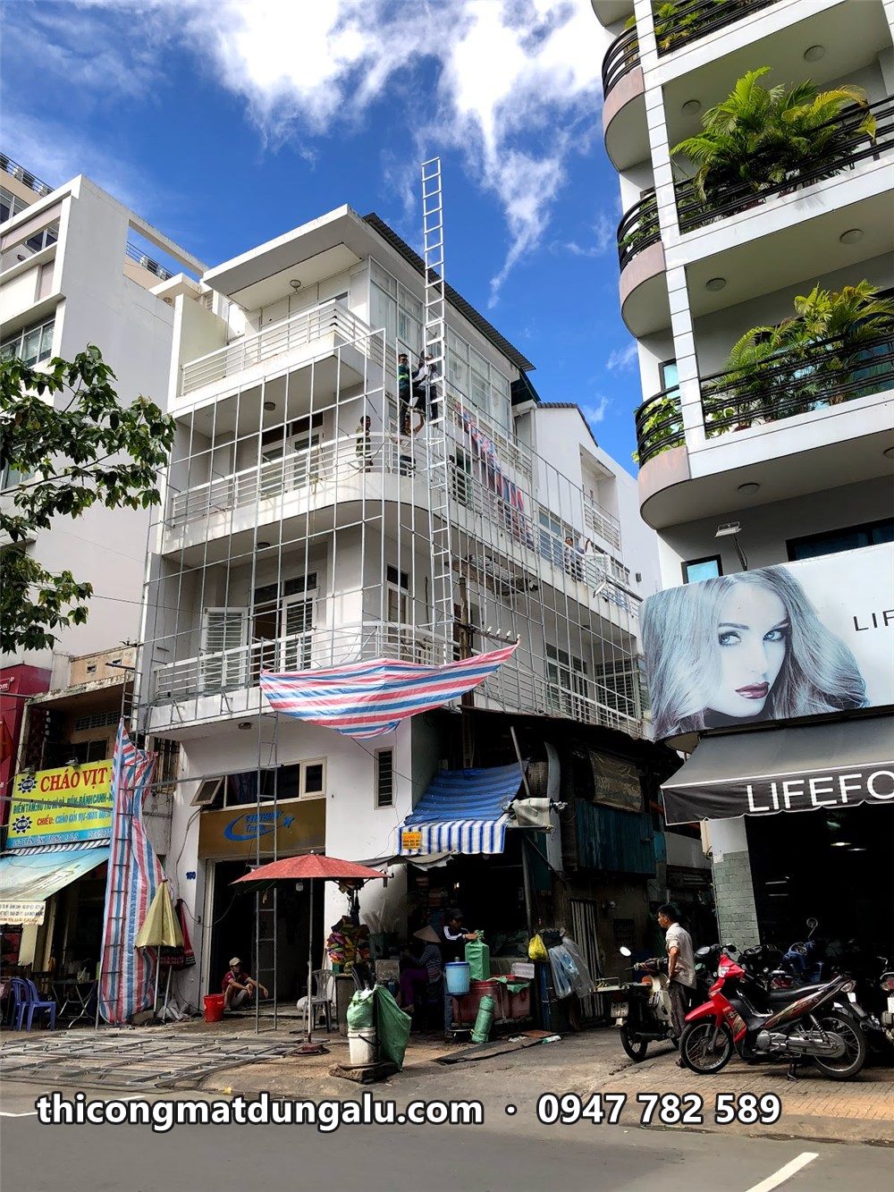 Nhà phố góc đường khi bắt đầu dựng giàn giáo, tấm bạt che ở tầng hai