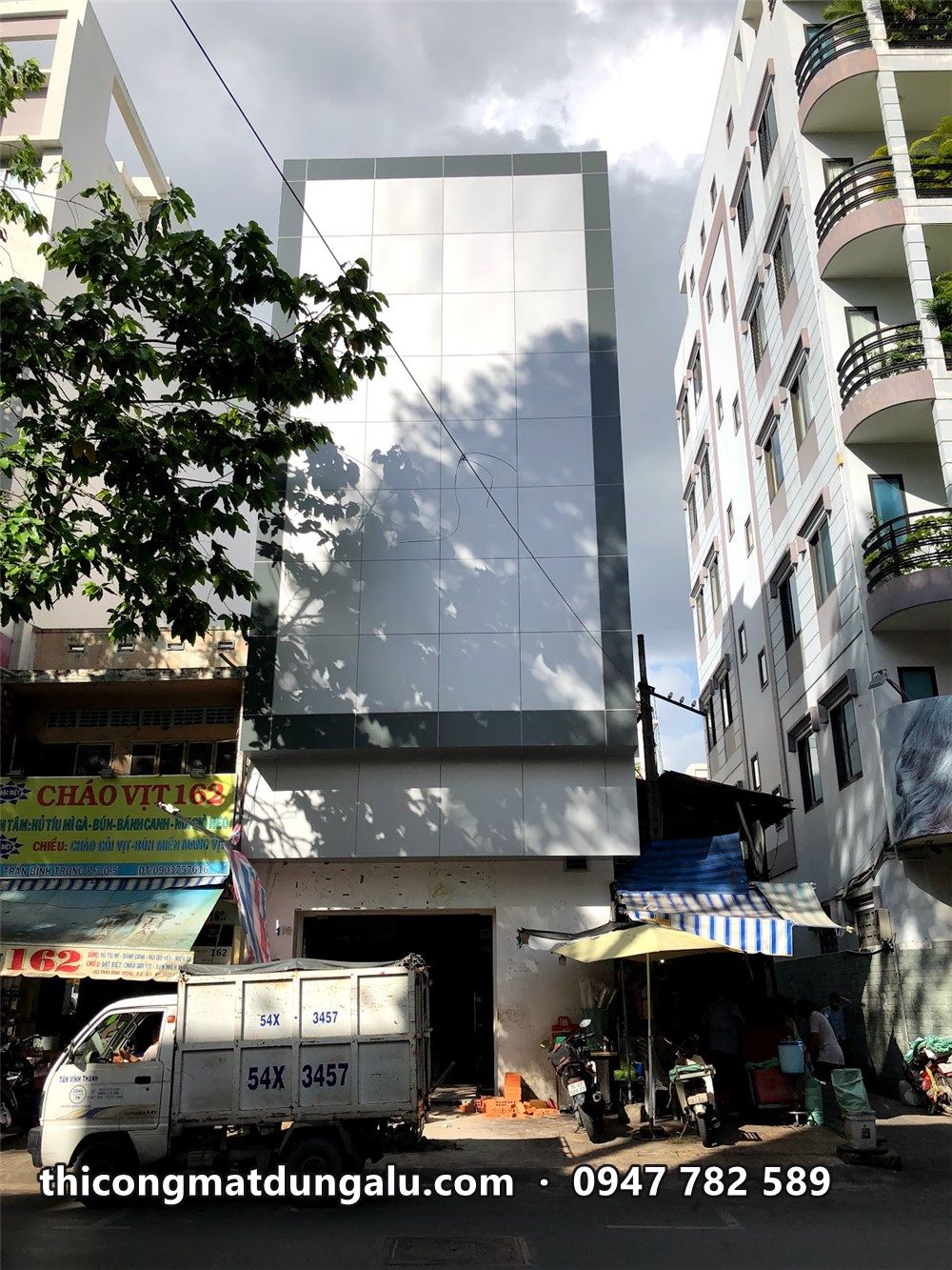 Nhà phố bọc alu hoàn thiện, xe tải nhỏ đậu trước cửa hàng tầng trệt