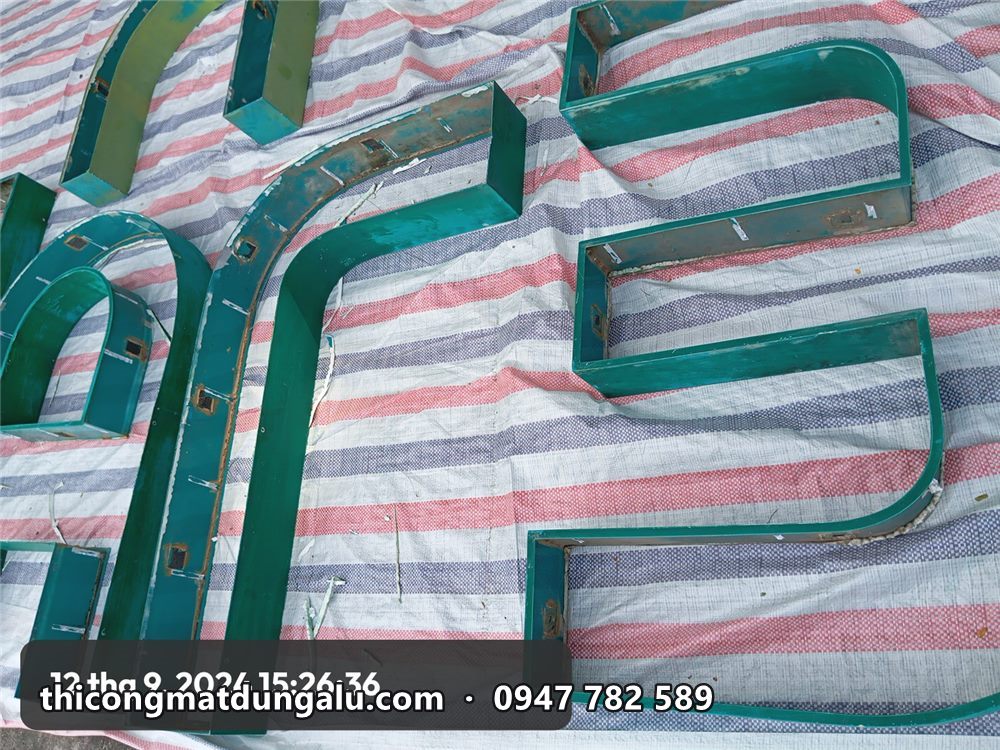 Khung chữ thép đã tháo hết đèn, trải trên bạt để cạo gỉ và xử lý bề mặt