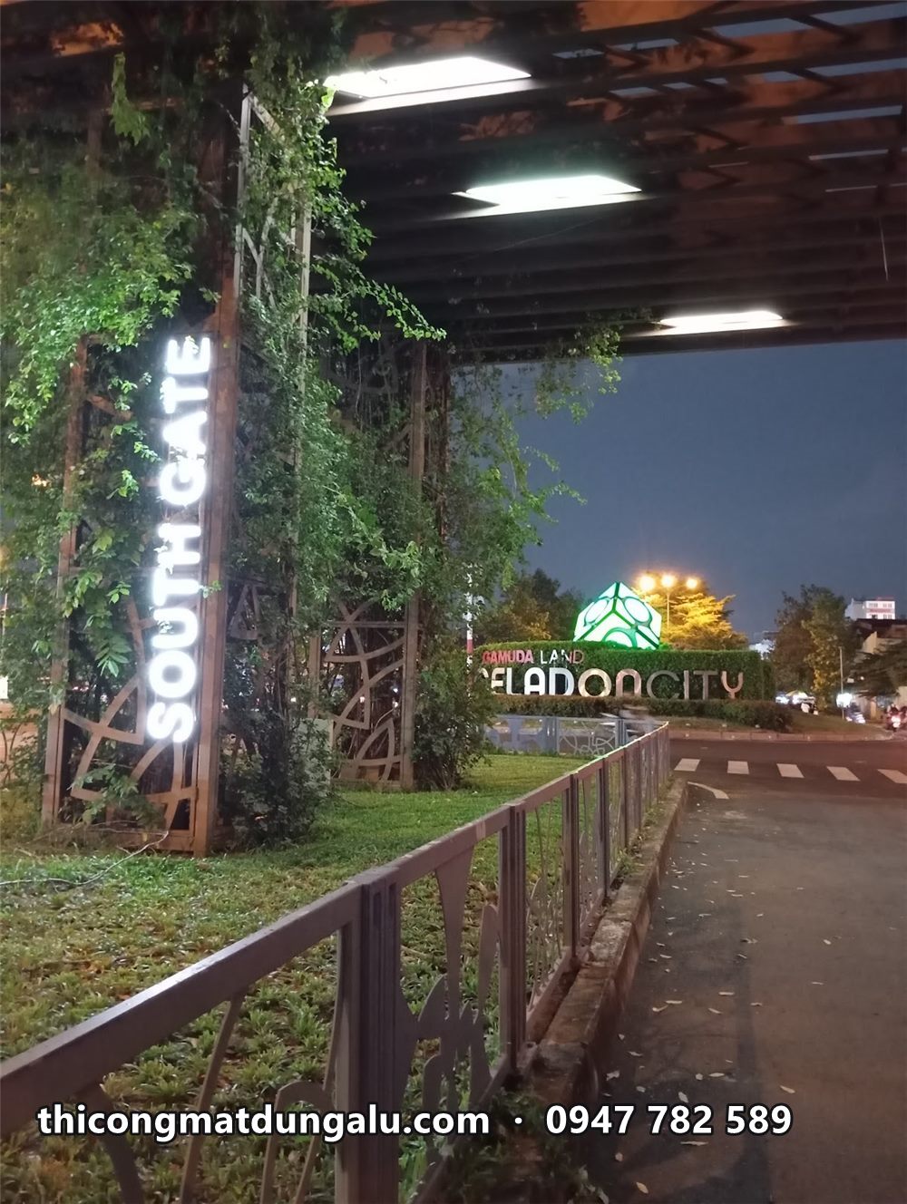 Chữ SOUTH GATE dọc trụ giàn cây leo sáng trắng ban đêm, phía xa là cụm chữ Celadon City