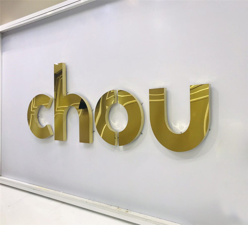 Chữ inox vàng gương gắn trên tường trắng