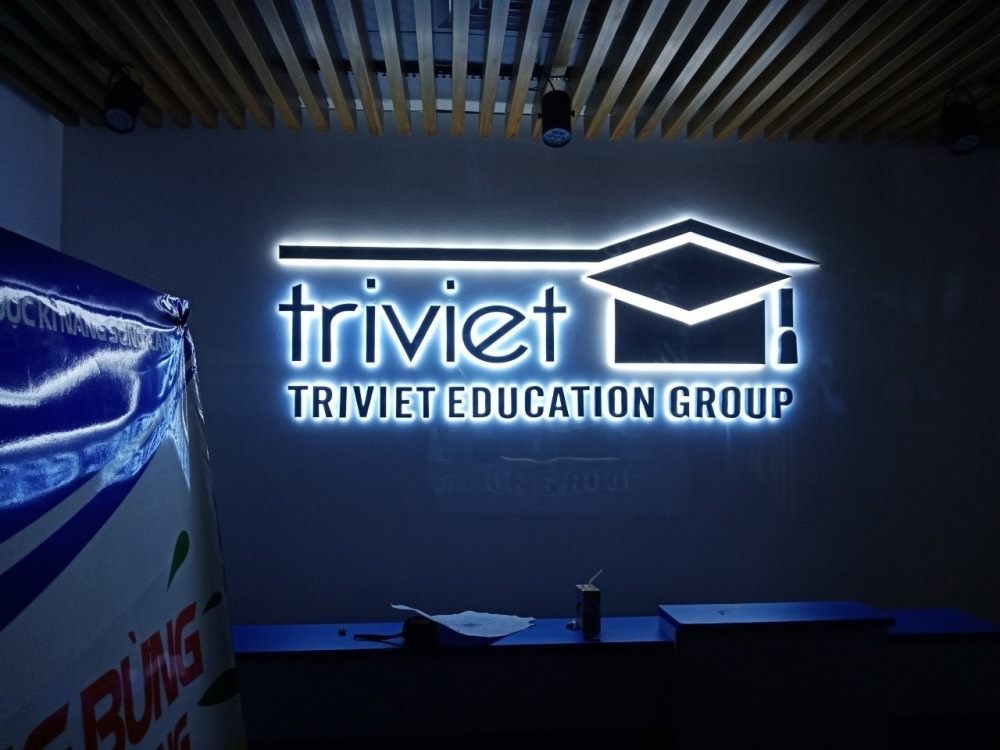 Logo và chữ hắt sáng trắng trên tường xanh đậm trong sảnh công ty