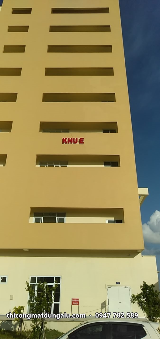 Chữ KHU E đỏ trên tường vàng của khối nhà cao tầng nhìn từ dưới lên