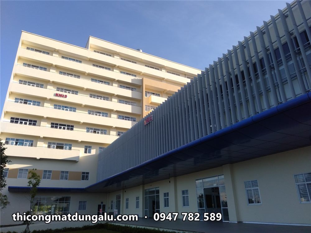 Khối nhà cao tầng và sảnh mái xanh của bệnh viện với chữ KHU trên tường
