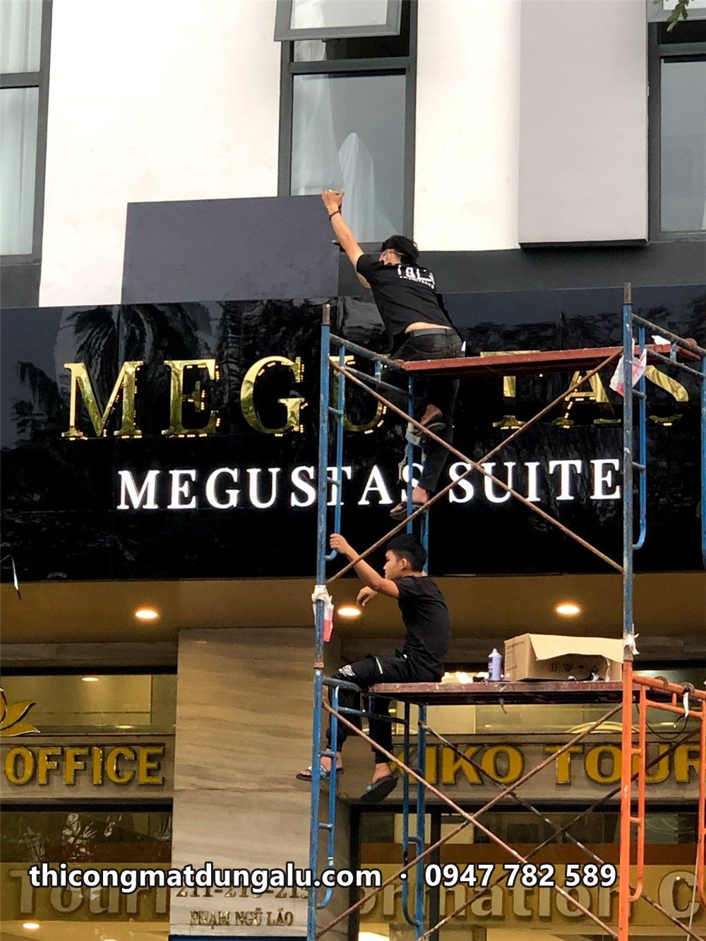Thợ trên giàn giáo lắp chữ Megustas vàng lên mái đón đen