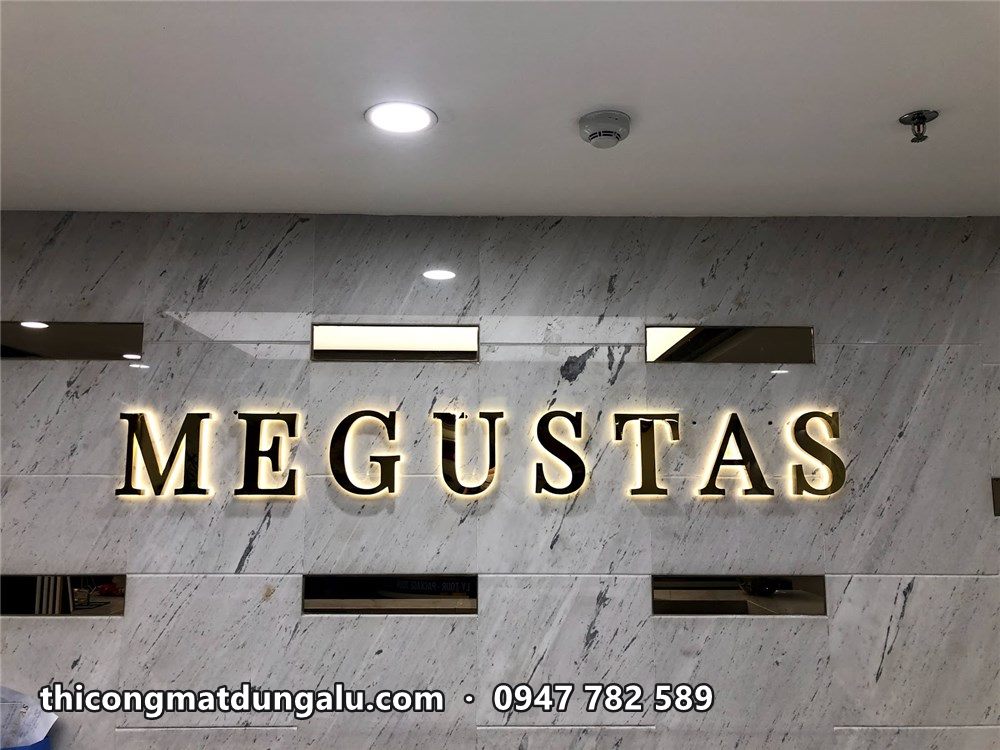 Chữ Megustas vàng hắt sáng trên vách đá trắng trong sảnh khách sạn