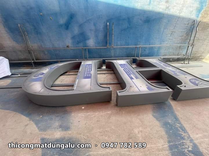 Hai chữ nổi khổ lớn thân xám đặt trên sân xưởng, chưa có mặt