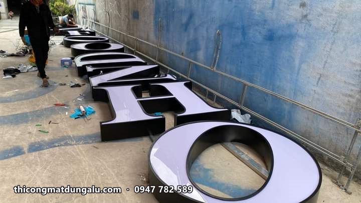 Dãy chữ nổi khổ lớn viền đen mặt trắng nằm dọc sân xưởng