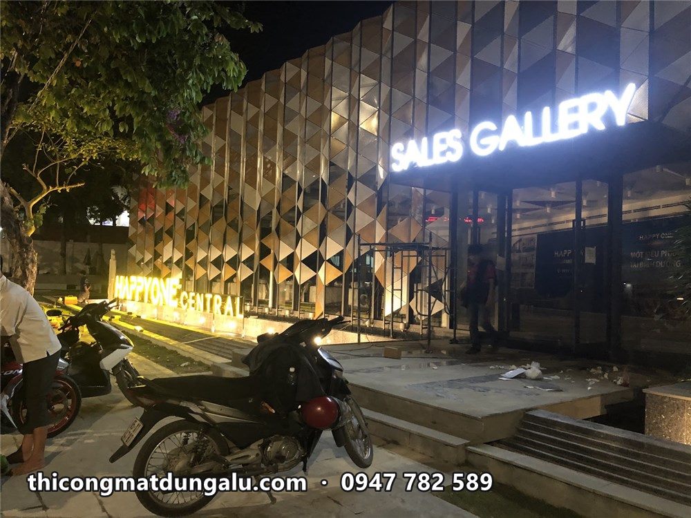 Góc nhà mẫu ban đêm với chữ Happy One Central và Sales Gallery cùng sáng