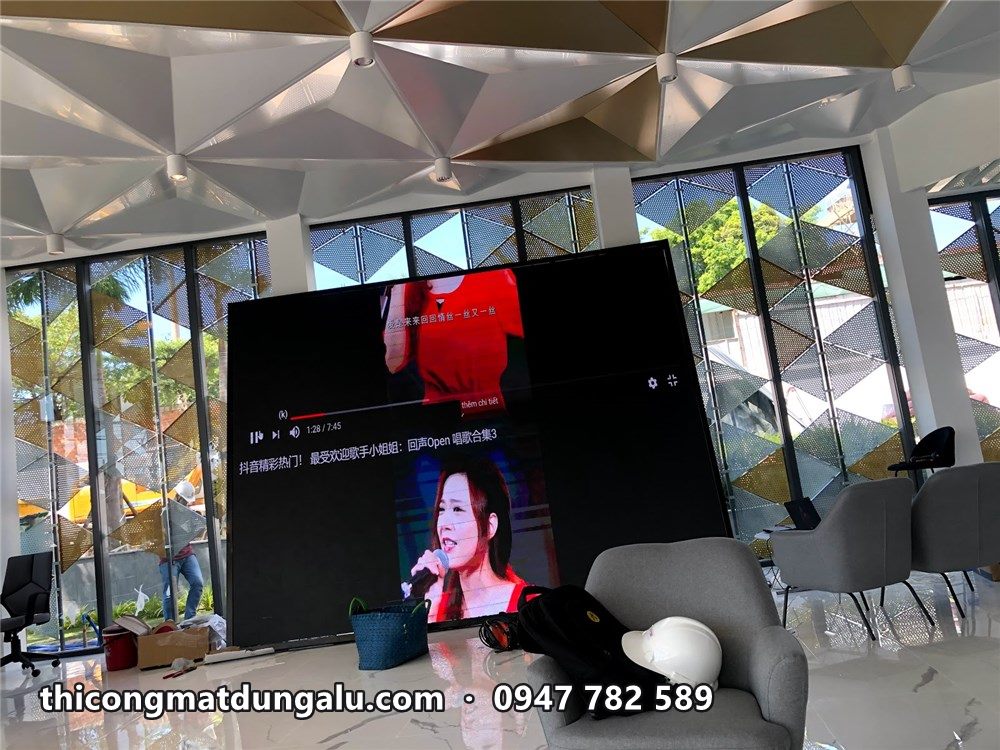 Kỹ thuật viên chạy thử màn hình LED lớn trong sảnh, mặt dựng tam giác phía sau