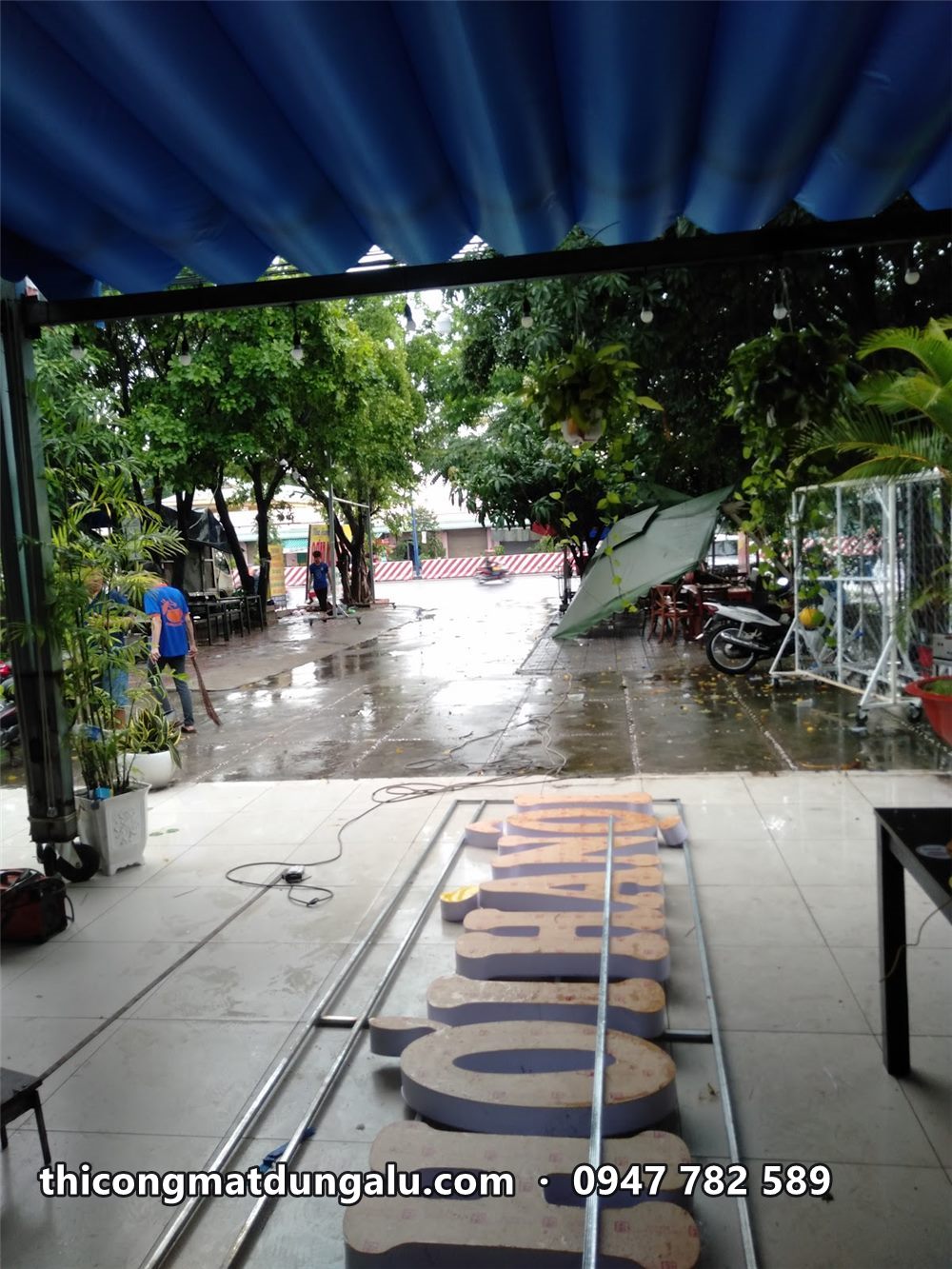 Khung chữ dài đặt trên sàn quán dưới mái tôn, phía trước là lối ra đường