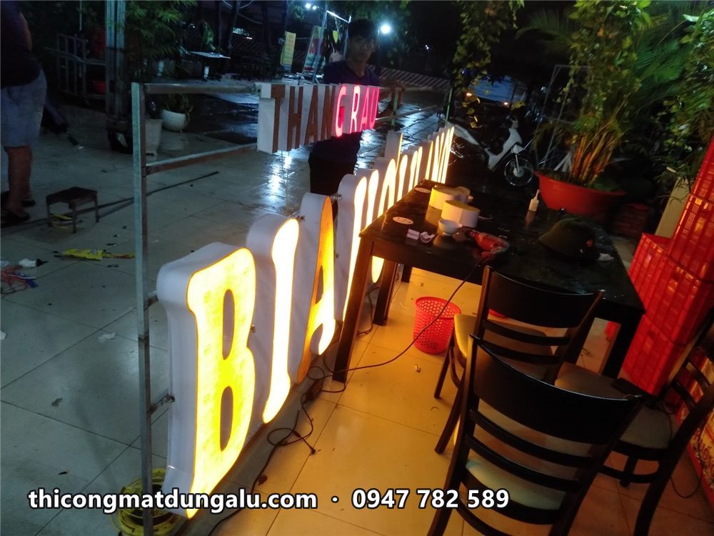 Cận cảnh chữ B, I, A sáng vàng trên khung, phía sau là bàn ghế quán