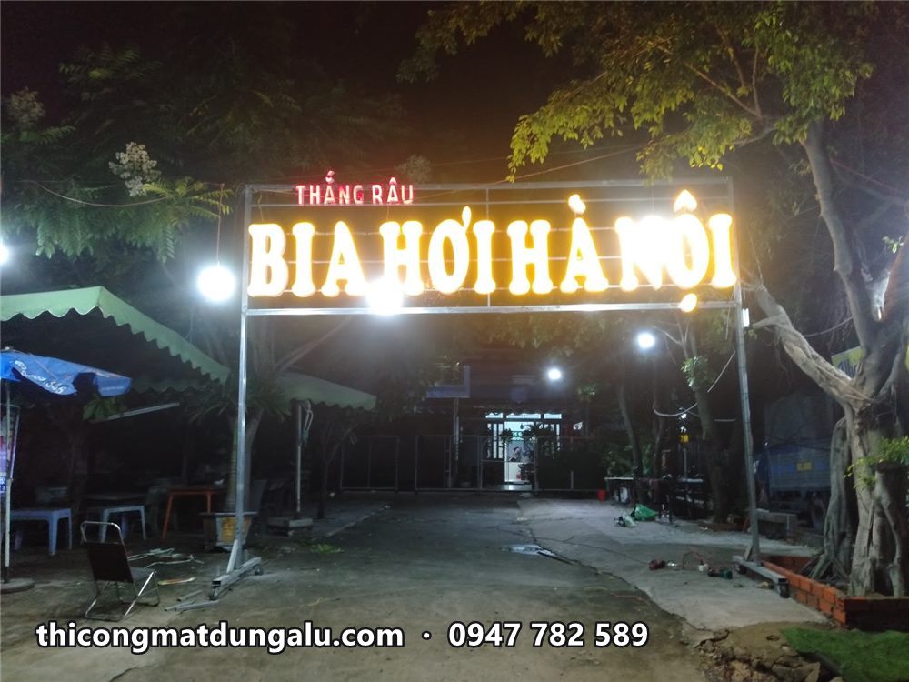 Cổng chữ BIA HƠI HÀ NỘI sáng vàng ban đêm trên hai trụ thép ở lối vào quán