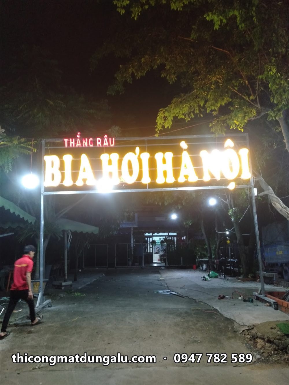 Cổng chữ Bia Hơi Hà Nội sáng đêm, người đi bộ qua bên dưới