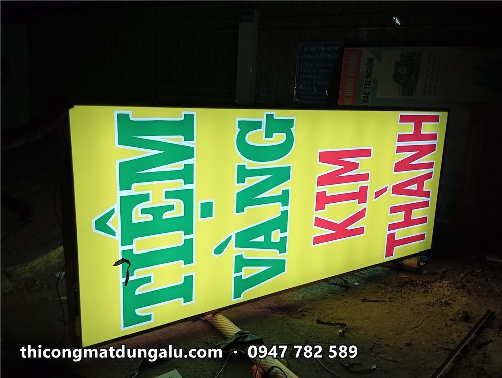 Hộp đèn Tiệm Vàng Kim Thành sáng đều, đặt nghiêng trên sàn xưởng