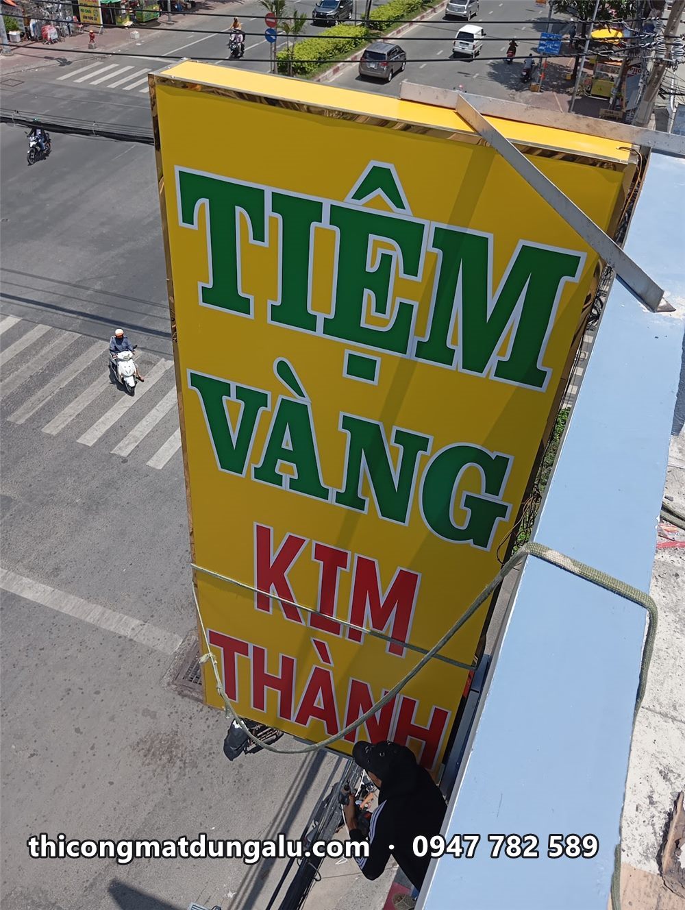 Hộp đèn dọc Tiệm Vàng Kim Thành treo trên mép nhà nhìn từ trên cao xuống đường