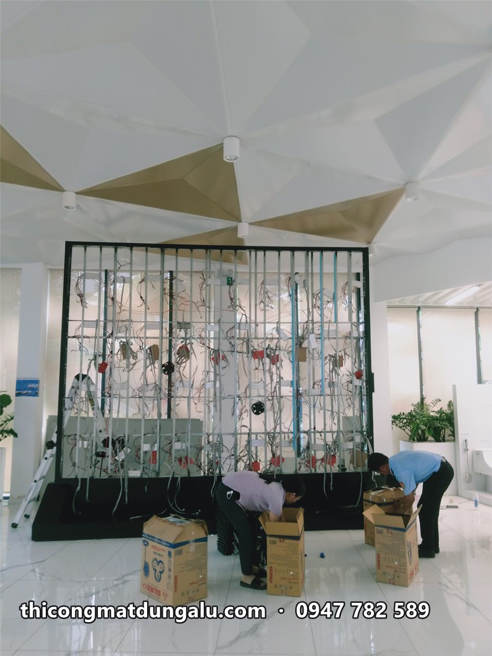 Khung module LED đang lắp dở giữa sảnh trần tam giác, các module chưa phủ kín