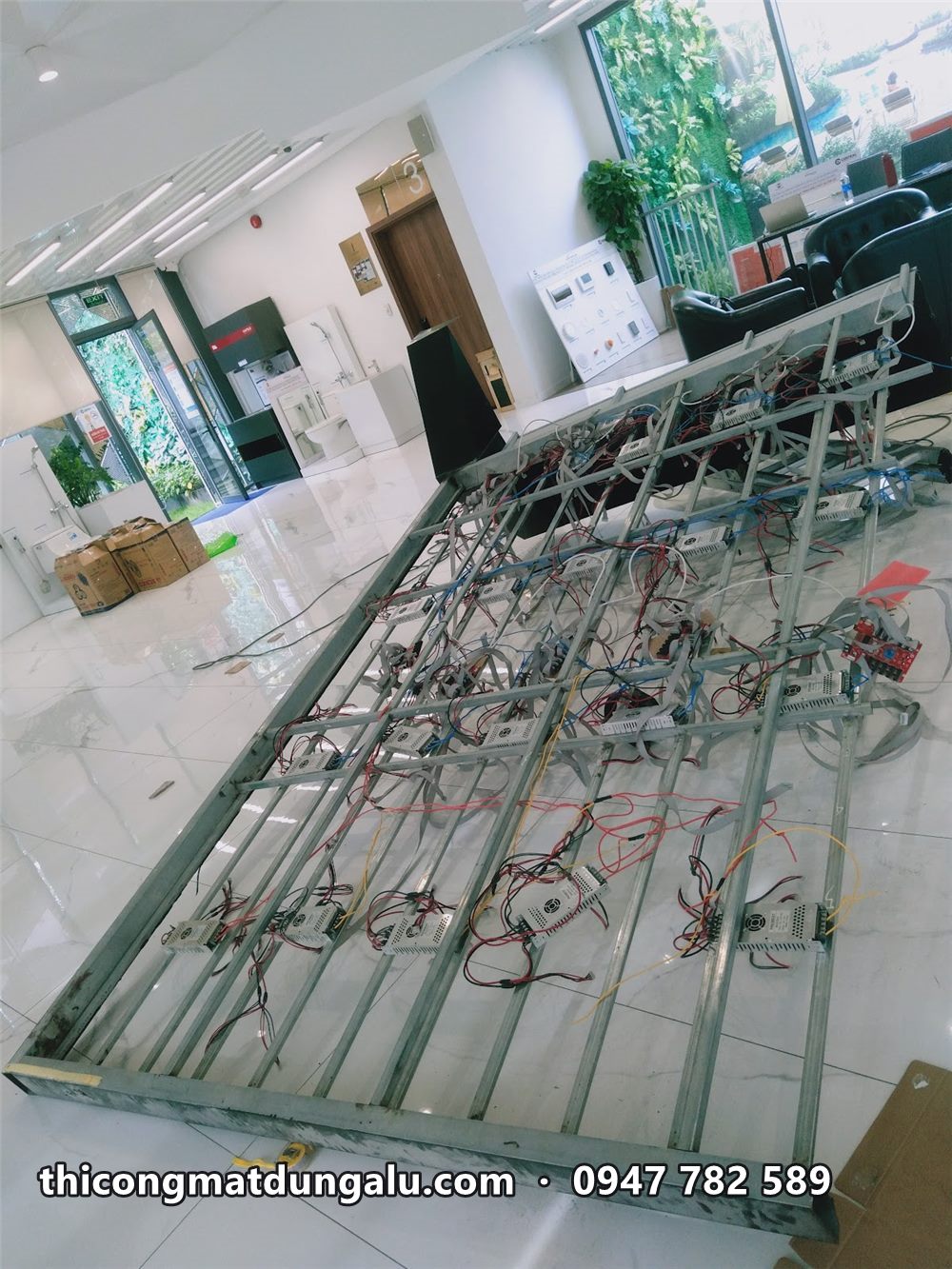 Khung sắt màn hình LED nằm trên sàn showroom, đang đi dây trước khi dựng