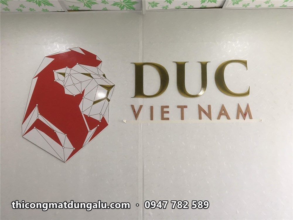 Logo DUC Việt Nam đầu sư tử đỏ và chữ vàng đồng trên tường trắng