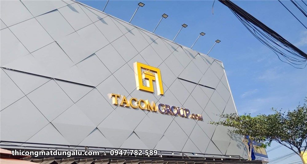 Cận cảnh logo Tacom Group vàng trên tấm ốp tam giác