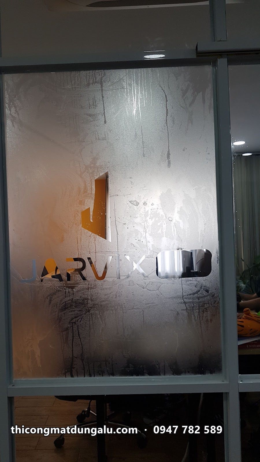 Logo Jarvix Labs cũ dạng decal trên vách, đã bong tróc nhiều mảng