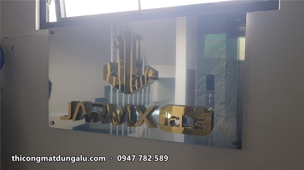 Logo Jarvix Labs inox vàng gắn trên tấm nền dưới khung cửa sổ, chưa bật đèn