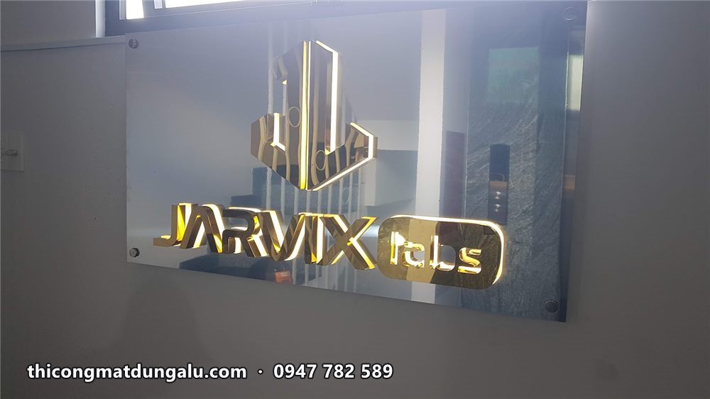 Logo Jarvix Labs inox vàng bật đèn hắt sáng nhẹ trên tấm nền