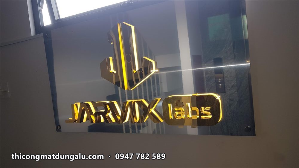 Logo Jarvix Labs inox vàng hắt sáng nhìn chính diện trong phòng