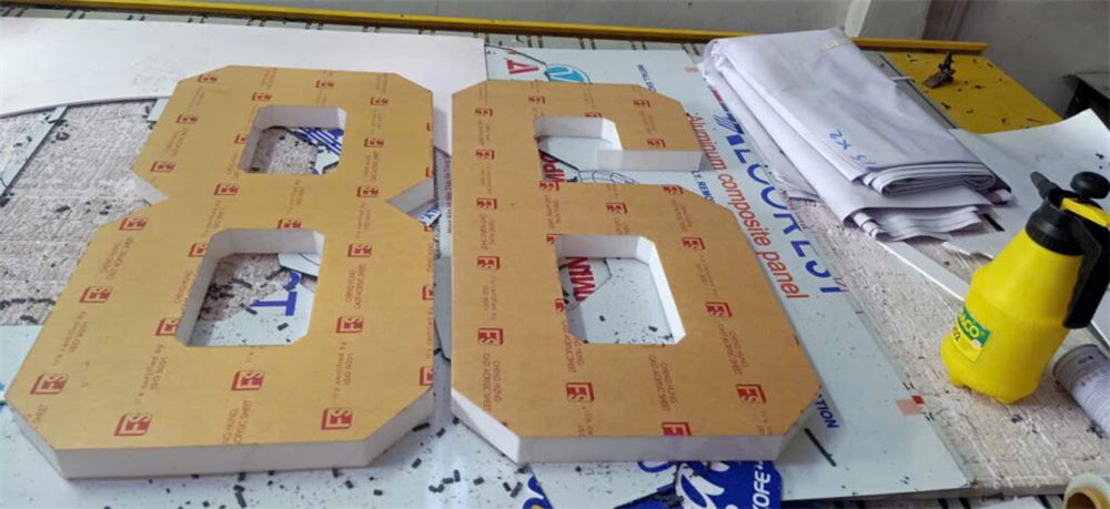 Chữ số cắt từ tấm vật liệu còn dán băng keo bảo vệ tại xưởng