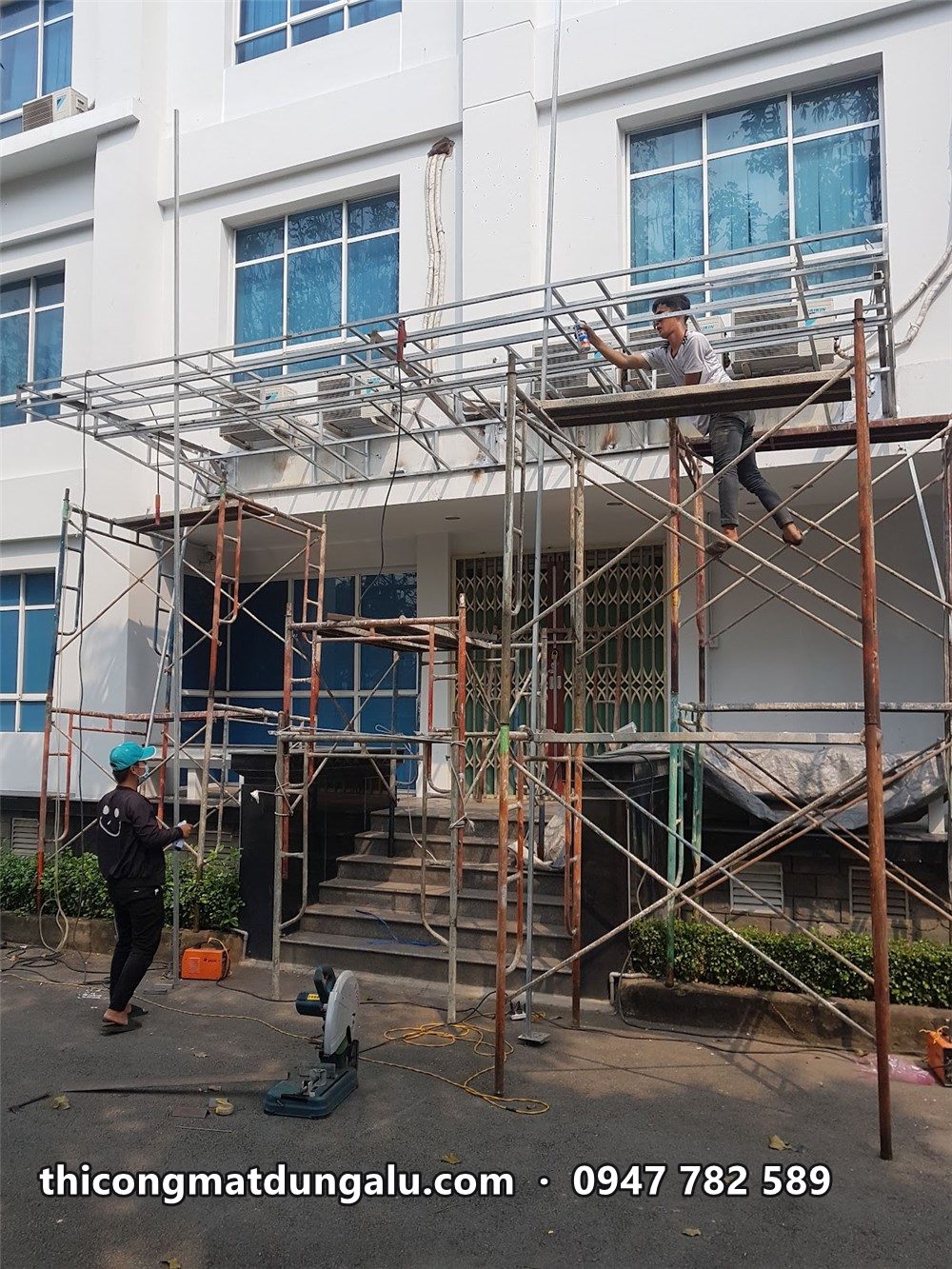 Giàn giáo dựng trước lối vào tòa văn phòng, thợ lắp khung mái sảnh