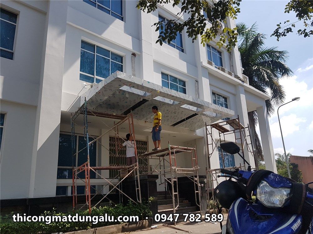 Mái đón lối vào tòa văn phòng đang ốp alu, thợ trên giàn giáo