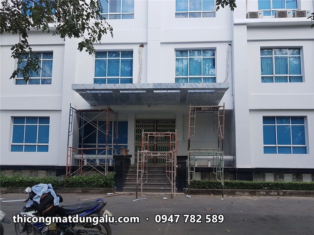 Mái đón ốp alu bạc trên lối vào, giàn giáo còn ở hai bên cửa