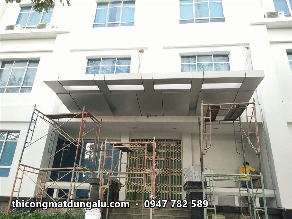 Mái đón alu bạc trên lối vào, giàn giáo đang tháo